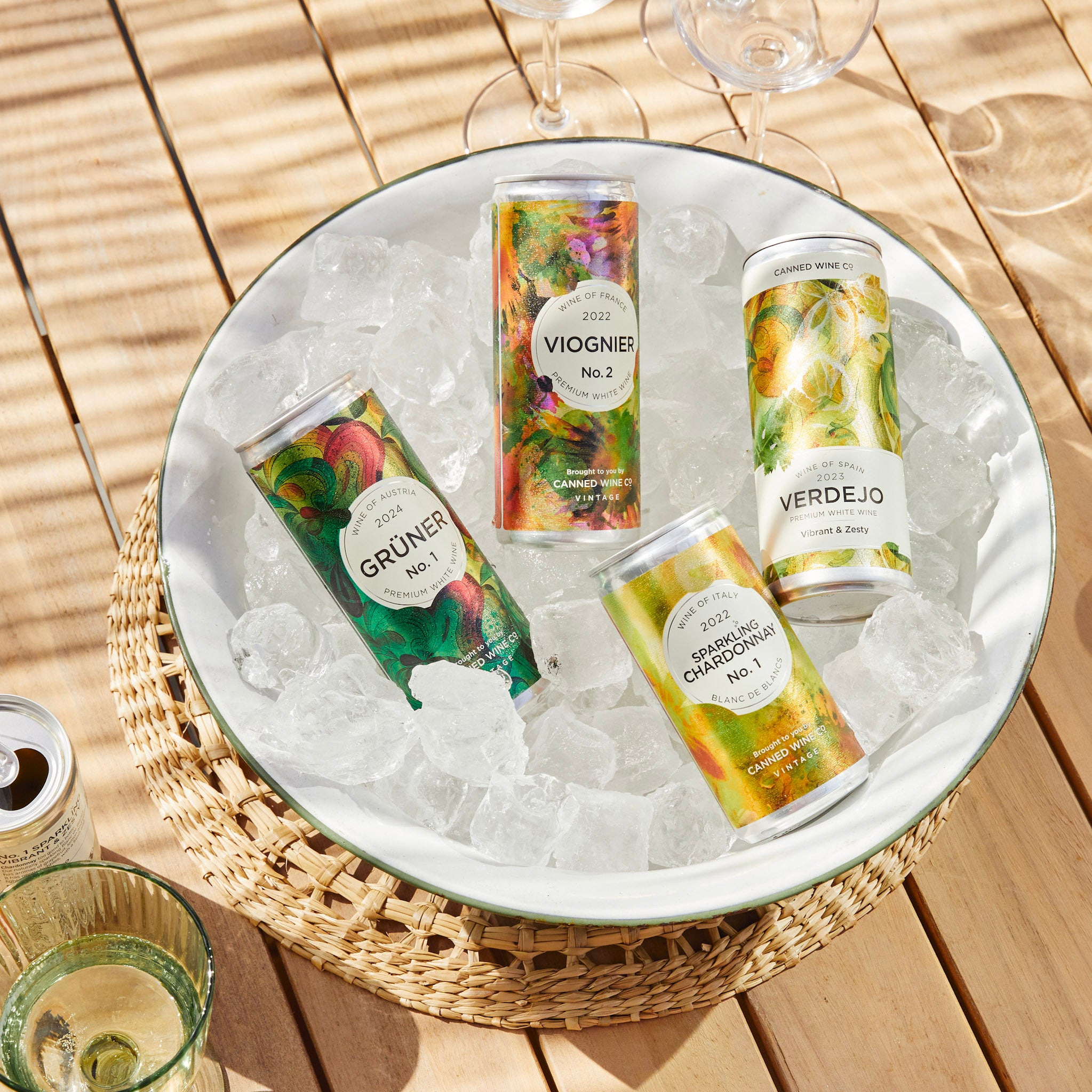 Cans of wine on ice in a round metal tray on a wooden surface